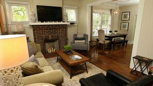 A living room with a fireplace, a television, a dining area with a table and chairs, and a sofa.