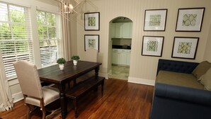 A dining area with a wooden table, chairs, and a bench. There are framed pictures on the wall.