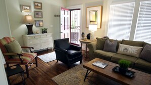 A living room with a sofa, armchair, coffee table, and a dresser.