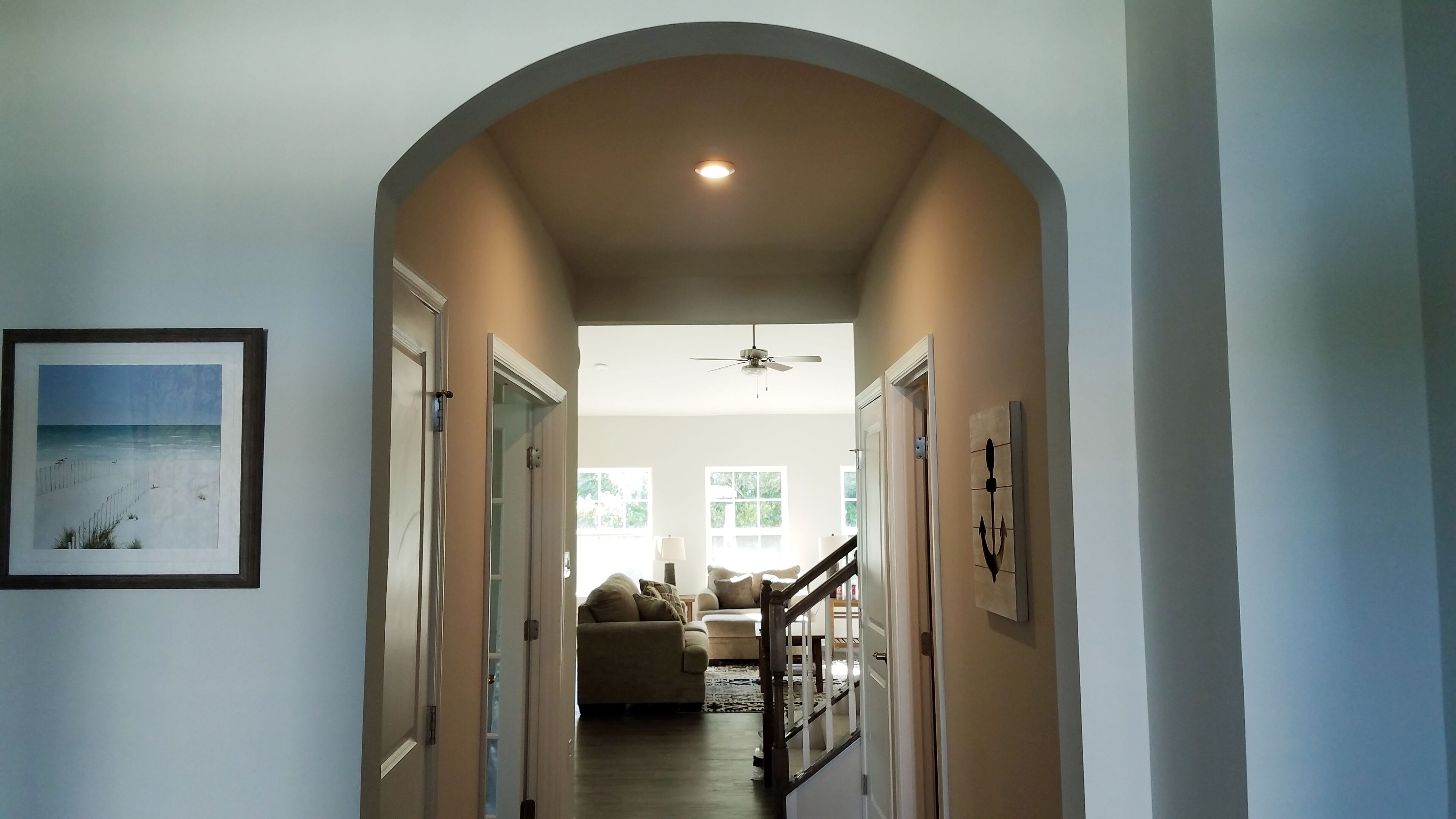 A hallway with an arched ceiling, a ceiling fan, and a framed picture on the wall.
