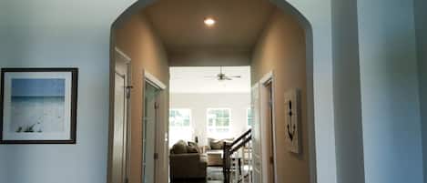 A hallway with an arched ceiling, a ceiling fan, and a framed picture on the wall.
