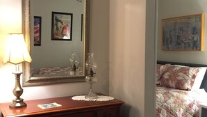 A bedroom with a wooden dresser, a mirror, and a bed with floral bedding. - Cowboy Cottage in Historic Downtown Prescott. Go to Whiskey Row! (Prescott)