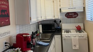 A kitchen with white cabinets, a red coffee maker, a gas stove, and a microwave. - Cowboy Cottage in Historic Downtown Prescott. Go to Whiskey Row! (Prescott)