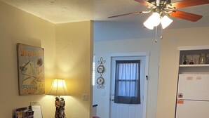 A living room with a beige sofa, a ceiling fan, a lamp, a door with a window, and a refrigerator. - Cowboy Cottage in Historic Downtown Prescott. Go to Whiskey Row! (Prescott)