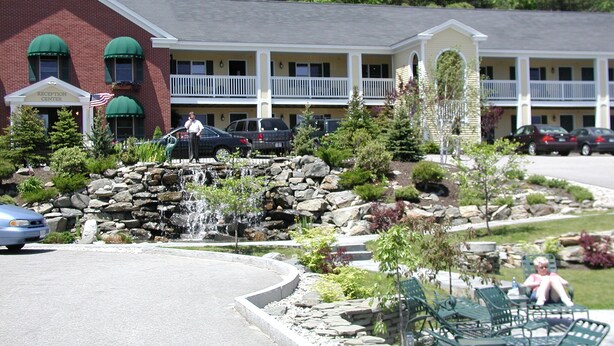 Un hôtel doté d’un espace de réception, de places assises en plein air et d’un jardin aménagé avec une petite cascade.