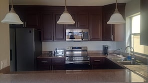 A kitchen with dark wooden cabinets, stainless steel appliances, and a granite countertop.