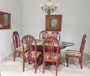 A dining area with a round table surrounded by six wooden chairs with cushioned seats.