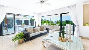 A spacious living room with a glass coffee table, a sofa, and a view of a pool and outdoor seating area.