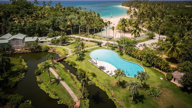 A resort with a large swimming pool, a beach, and a tropical setting.