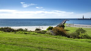 Een kustlandschap met een strand, grasvelden en een spoorlijn.