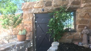 A stone building with a black door, a potted cactus, and a statue.