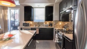 A modern kitchen with dark cabinetry, a central island, a stove, and a refrigerator.