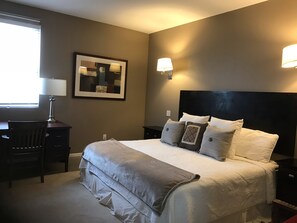 A neatly arranged bedroom with a large bed, bedside lamps, a desk, and a chair. - Truly unique art-filled home w/ garden close to the Plaza. (SANTA FE)