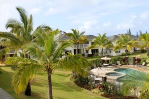A resort with a pool area, palm trees, and a two-story building. - Gorgeous, 3 private suites. Balcony View, Pool, Fitness Center! (Princeville)