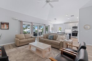 A modern living room with a sofa set, a coffee table, and a dining area with a kitchen in the background.