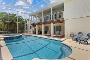 A swimming pool with a glass ceiling, lounge chairs, and a view of palm trees. - Hidden Treasure is ready for your stay (Fort Myers Beach)