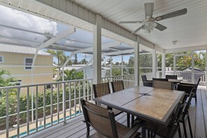 A covered outdoor area with a table and chairs, a ceiling fan, and a view of the surrounding landscape.