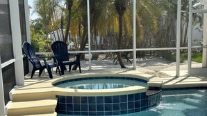 A pool with a tiled edge, surrounded by chairs and palm trees. - Hidden Treasure is ready for your stay (Fort Myers Beach)