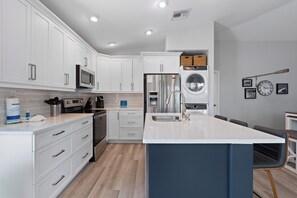 A modern kitchen with white cabinets, stainless steel appliances, and a central island.