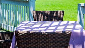 Ein Sitzbereich im Freien mit Korbmöbeln und einem Tisch, der mit einer violetten Tischdecke bedeckt ist.