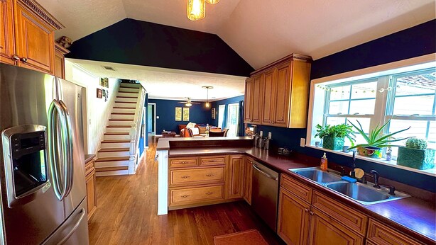 Eine moderne Küche mit Holzausstattung, einem Edelstahlkühlschrank und einem eingebauten Backofen.
