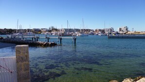 A marina with boats docked, clear water, and buildings in the background.