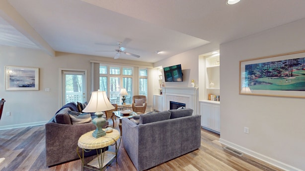 A spacious living room with a fireplace, comfortable seating, and large windows.