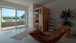 A modern living room with a wooden bench, a potted plant, and a bookshelf. - Cherry Tree With Pool Near Split (Donje Sitno)