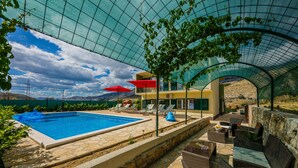 A pool area with lounge chairs and umbrellas, surrounded by stone walls and greenery. - Cherry Tree With Pool Near Split (Donje Sitno)