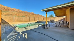 A swimming pool with a patio area, outdoor seating, and a view of a mountainous landscape. - Mountain-View Moab Home w/ Pool & Hot Tub Access! (Moab)