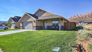 A residential house with a garage, a covered porch, and a well-maintained lawn. - Mountain-View Moab Home w/ Pool & Hot Tub Access! (Moab)