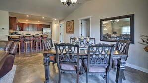 A spacious dining area with a large wooden table and matching chairs, a kitchen in the background, and a large mirror on the wall. - Mountain-View Moab Home w/ Pool & Hot Tub Access! (Moab)