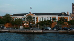 A waterfront building with a symmetrical facade, large windows, and a flagpole. - ⭐ Blue Bay BEACH villa, minutes walk to beach/pool/golf⭐ 🧡 3BR/2BA (Blue bay golfresort)