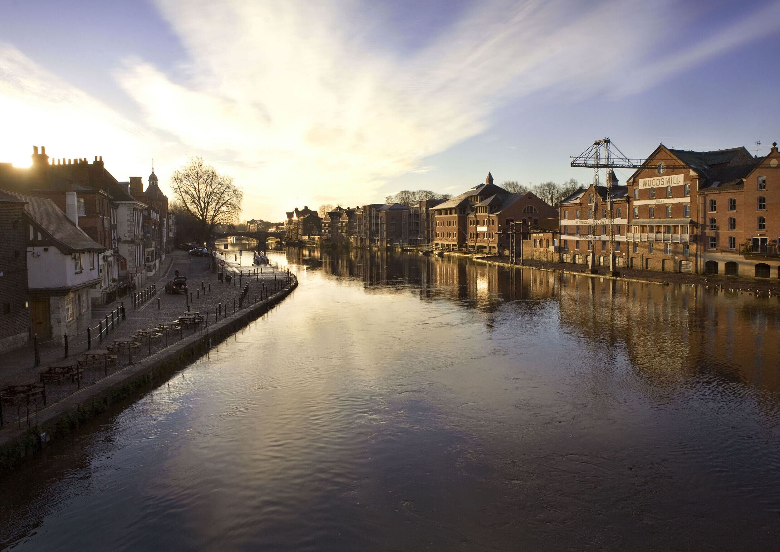 A riverside view of a historic town with traditional architecture, a bridge, and a canal.