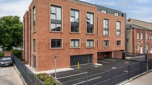 A modern brick building with multiple windows and a parking area.
