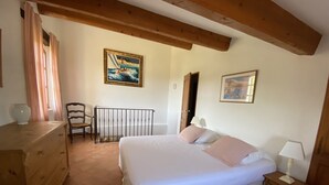 A bedroom with a bed, dresser, chair, and two paintings on the wall. - *** Les BOUTINELLES * Superb apartment in LA FERME DU MOULIN ROUX (Ramatuelle)
