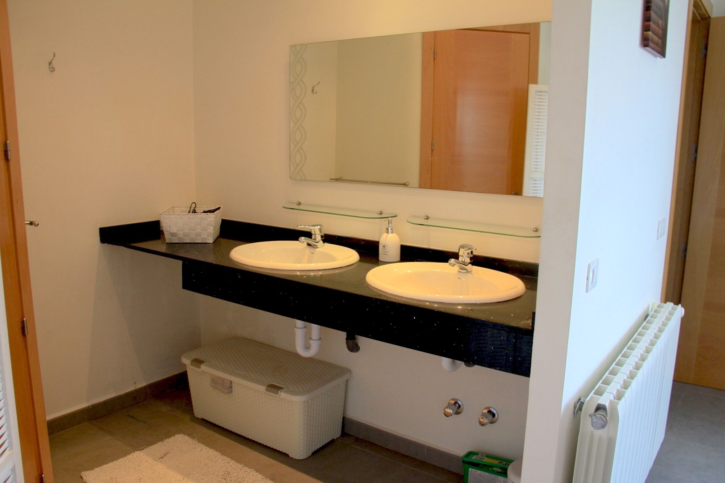 A bathroom with two sinks, a mirror, and a towel rack.