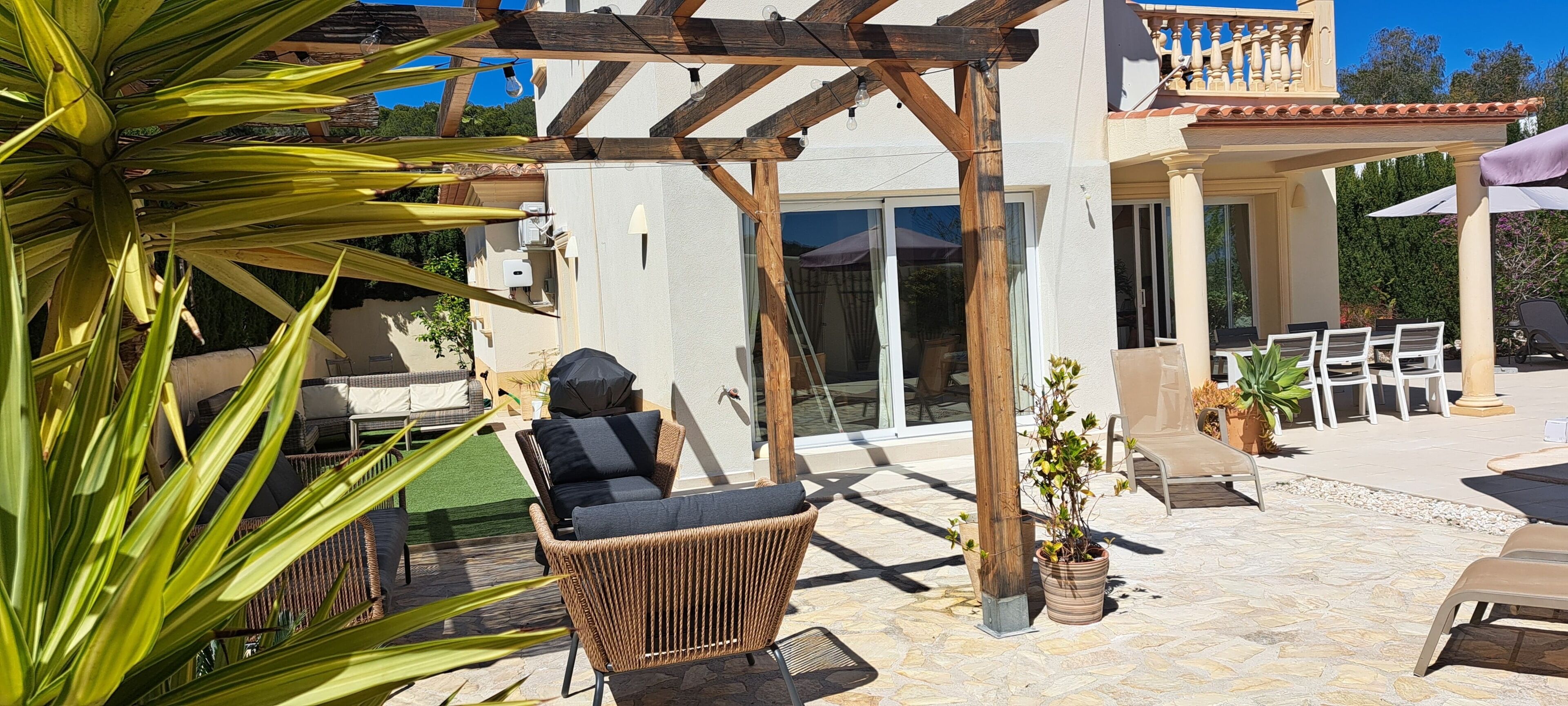 Eine Terrasse mit Korbstühlen, einer Schaukel und Blumentöpfen.