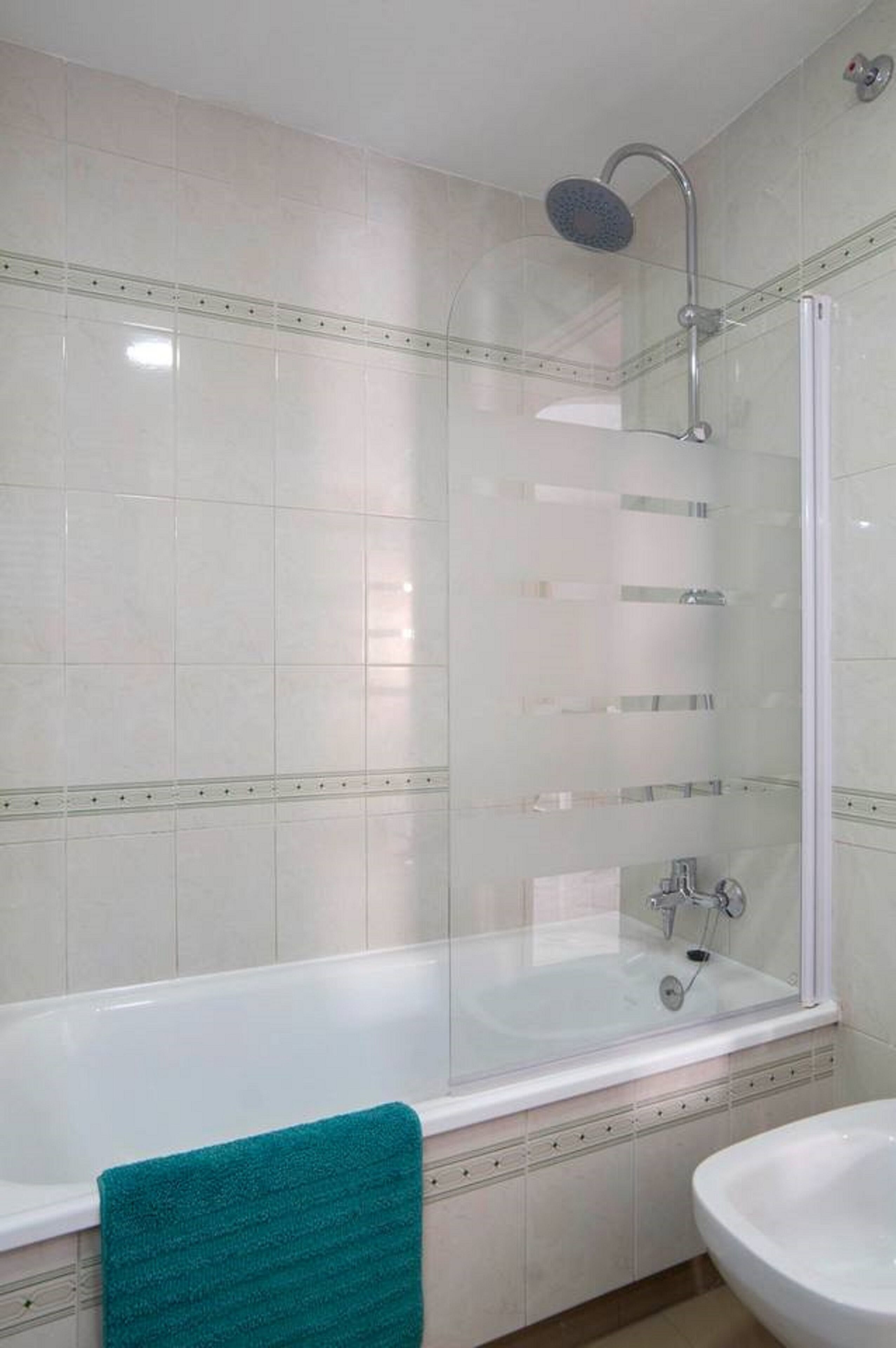 Een badkamer met een douche in glazen cabine, een bad en een wastafel.