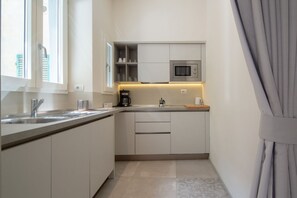 A modern kitchen with a built-in microwave, a coffee maker, and a window with blinds.