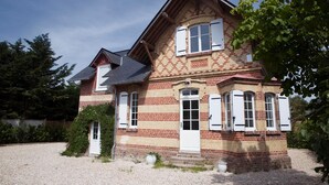 A two-story house with a brick facade, white shutters, and a gravel driveway. - Charming Villa with Garden near the beach (Tourgéville)