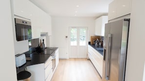 A modern kitchen with white cabinets, a stainless steel refrigerator, and a black countertop. - Charming Villa with Garden near the beach (Tourgéville)