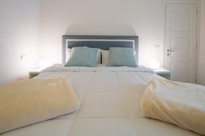 Un lit avec une tête de lit blanche et bleue, deux tables de chevet avec des lampes et une porte blanche.