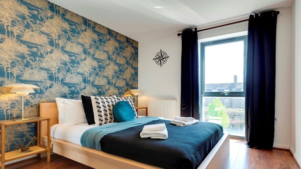 Una camera d'hotel moderna con un letto grande, vista sulla città e una parete decorativa.