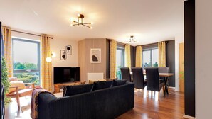 Un soggiorno moderno con divano, televisione e zona pranzo.