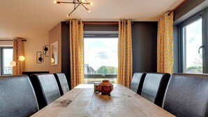 Una sala conferenze con un tavolo in legno, sedie imbottite grigie, tende a motivi e una vista attraverso ampie finestre.