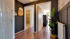 Un corridoio con pavimento in legno, una porta bianca, uno specchio e un termosifone.