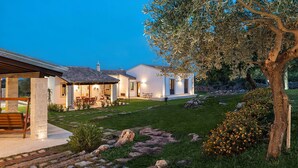 Ein modernes Haus mit Terrasse, Sitzgelegenheit im Freien und einem gepflegten Garten.