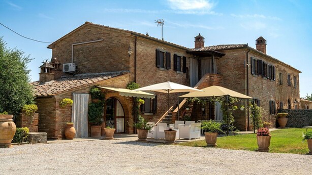 A traditional brick building with a patio area featuring outdoor seating and umbrellas.
