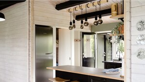 Una cocina con encimera de madera, dos taburetes, un refrigerador y lámparas colgantes.